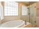 Bright bathroom featuring a soaking tub, a glass shower and a decorative glass block window for privacy at 15107 E Desert Willow Dr, Fountain Hills, AZ 85268