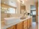 Well-lit bathroom featuring double sinks, a large mirror, white countertops and wood cabinetry at 15107 E Desert Willow Dr, Fountain Hills, AZ 85268