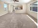 Bright, open-concept living room featuring large windows and neutral carpeting at 15369 W Wethersfield Rd, Surprise, AZ 85379