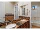 Bathroom with double sinks, granite countertop, brown cabinetry, decorative backsplash, and view to shower and toilet room at 1713 W Calle Marita --, Phoenix, AZ 85085