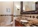 Powder room with a decorative mirror, granite countertop, and tile accents at 1713 W Calle Marita --, Phoenix, AZ 85085