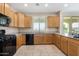 Well-lit kitchen featuring granite countertops, light wood cabinets, and modern black appliances at 17425 W Willow Ave, Surprise, AZ 85388