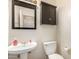 Well-lit half bath features a pedestal sink, toilet, and cabinet at 18492 E Oak Hill Ln, Queen Creek, AZ 85142