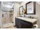 Bathroom with a stylish vanity, dual sinks, framed mirrors, and a modern shower with decorative tile accents at 18802 N 71St Ln, Glendale, AZ 85308