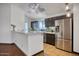 Bright kitchen featuring stainless steel appliances, brown cabinets, and a breakfast bar, with modern lighting fixtures at 18802 N 71St Ln, Glendale, AZ 85308