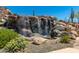 Beautiful rock waterfall feature with lush greenery providing a serene and natural ambiance at 1919 W Plum Rd, Phoenix, AZ 85085