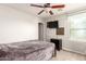 Neutral-toned bedroom features a ceiling fan, mounted TV, and window with paneled accents at 20709 W Delaney Dr, Buckeye, AZ 85396