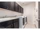 Functional laundry room with dark cabinets, sink, and modern washer and dryer appliances at 20709 W Delaney Dr, Buckeye, AZ 85396