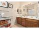 Well-lit bathroom with double sinks, wood cabinets, and decorative shelving at 21563 N Greenway Rd, Maricopa, AZ 85138