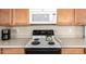 Bright kitchen featuring an electric range, microwave, light countertops, and wooden cabinets at 21563 N Greenway Rd, Maricopa, AZ 85138