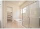 Relaxing bathroom featuring a soaking tub, glass-enclosed shower, and a convenient walk-in closet for storage at 2406 N 142Nd Ave, Goodyear, AZ 85395