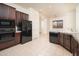 Well-equipped kitchen featuring dark cabinetry, granite countertops, tile flooring, and stainless steel appliances at 2406 N 142Nd Ave, Goodyear, AZ 85395