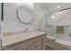 Bathroom showcasing a round mirror, large vanity, and a walk-in shower with glass doors at 3830 E Lakewood E Pkwy # 1007, Phoenix, AZ 85048