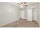 A neutral bedroom featuring a ceiling fan and sliding closet doors, carpeted for comfort at 635 N Yale Dr, Gilbert, AZ 85234
