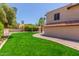 Lush backyard featuring verdant lawn, mature trees, and a brick pathway leading to the side of the house at 635 N Yale Dr, Gilbert, AZ 85234