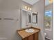 Bathroom with decorative framed mirror and a vanity with a white sink, alongside the toilet and an exterior view at 6469 W Ruth Ave, Glendale, AZ 85302