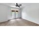 Bright bedroom featuring neutral carpet, ceiling fan, and doors to a private balcony at 7217 S Hazelton Ln, Tempe, AZ 85283