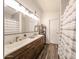 Modern bathroom featuring double sinks, sleek fixtures, wood floors, and shower with curtain at 8521 W Mauna Loa Ln, Peoria, AZ 85381