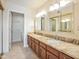 Bathroom with double sinks, wood cabinets and granite countertop next to walk-in closet and toilet at 9463 E Jenan Dr, Scottsdale, AZ 85260