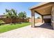 A pristine backyard with green lawn, covered patio, brickwork and mature trees under a clear blue sky at 9837 E Tiburon Ave, Mesa, AZ 85212
