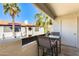 Balcony with a table and chairs and a view of palm trees and a building with a red tile roof at 9990 N Scottsdale Rd # 2042, Paradise Valley, AZ 85253