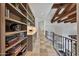 Upstairs hallway features custom bookshelves, wood beams, tile floors, and iron railing at 10182 E Gilded Perch Dr, Scottsdale, AZ 85255
