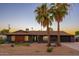 Charming single-story home with desert landscaping, mature palm trees, dark exterior paint, and a two-car garage at 10240 N 34Th Pl, Phoenix, AZ 85028