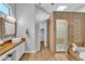 Bathroom with double vanity, tub, and walk-in shower with beautiful decorative tile work at 10809 W Harmony Ln, Peoria, AZ 85373