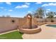 Backyard view of a decorative water feature set against a block wall with a sun decoration at 10809 W Harmony Ln, Peoria, AZ 85373