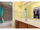 Well-lit bathroom featuring a wood vanity, large mirror, and a shower-tub with gray tiled walls at 1111 W Summit Pl # 85, Chandler, AZ 85224