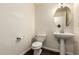 A bathroom showcases a pedestal sink, decorative mirror, and a white toilet at 11429 W Yavapai St, Avondale, AZ 85323