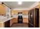 Functional kitchen with wood cabinets, black appliances, light countertops, and wood floors at 11429 W Yavapai St, Avondale, AZ 85323