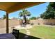 Outdoor dining area with a stone patio, metal table and chairs, and a palm tree under a clear blue sky at 1212 W Vera Ln, Tempe, AZ 85284