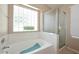 Bright bathroom with a large tub, glass block window, and walk-in shower at 1212 W Vera Ln, Tempe, AZ 85284