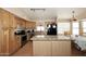 Open kitchen featuring an island, wood cabinets, stainless steel appliances, and laminate floors for easy cleaning at 1212 W Vera Ln, Tempe, AZ 85284