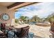 A picturesque backyard featuring a pool, spa, travertine tile, and a covered patio with outdoor seating at 12381 S 182Nd Dr, Goodyear, AZ 85338