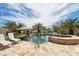 Resort-style pool area with travertine tile, lush palm trees, and comfortable lounge chairs at 12381 S 182Nd Dr, Goodyear, AZ 85338