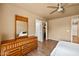 This bedroom has wood floors, a ceiling fan, and a dresser with a mirror at 12621 W Willow Ave, El Mirage, AZ 85335