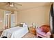 A cozy bedroom has wood floors, a ceiling fan, and a peach-colored chair at 12621 W Willow Ave, El Mirage, AZ 85335