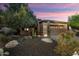 Charming home with desert landscaping, including a mature tree and various cacti at dusk at 12972 W Kokopelli Dr, Peoria, AZ 85383