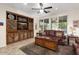 Cozy living room featuring tile flooring, a ceiling fan, large windows, and a built-in entertainment center at 12972 W Kokopelli Dr, Peoria, AZ 85383