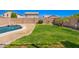 A private backyard featuring a sparkling pool, lush lawn, and mature landscaping at 17258 W Meghan Dr, Goodyear, AZ 85338