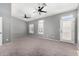 Spacious bedroom with two ceiling fans, carpet, and ample natural light from multiple windows and a glass door at 17258 W Meghan Dr, Goodyear, AZ 85338