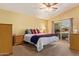 Bright bedroom with a ceiling fan, sliding glass door, and a comfortable bed with colorful pillows and blankets at 174 W Del Rio St, Gilbert, AZ 85233