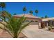 Charming home with a two-car garage, front yard landscaping including grass, bushes, gravel, and palm trees at 174 W Del Rio St, Gilbert, AZ 85233