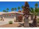 Charming home with a two-car garage, front yard landscaping including grass, bushes, gravel, and palm trees at 174 W Del Rio St, Gilbert, AZ 85233