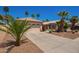 Charming home with a two-car garage, front yard landscaping including grass, bushes, gravel, and palm trees at 174 W Del Rio St, Gilbert, AZ 85233