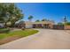 Inviting home featuring a spacious driveway, mature trees, and charming landscaping, set against a clear blue sky at 1817 W Seldon Ln, Phoenix, AZ 85021
