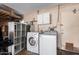Laundry room includes a washer, dryer, storage shelves, and white cabinets for supplies at 1817 W Seldon Ln, Phoenix, AZ 85021