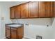Well-lit laundry room with overhead cabinets and a utility sink at 18617 E Arrowhead Trl, Queen Creek, AZ 85142